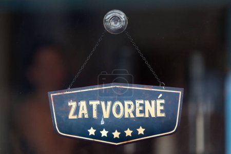 Old fashioned sign in the window of a shop saying in Slovak "Zatvorene", meaning in English "Closed".