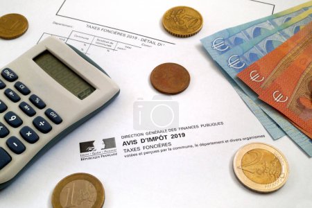 Ein Taschenrechner und ein paar Euromünzen und Banknoten auf der Oberseite eines französischen Grundsteuerformulars (Avis de Taxes foncieres).