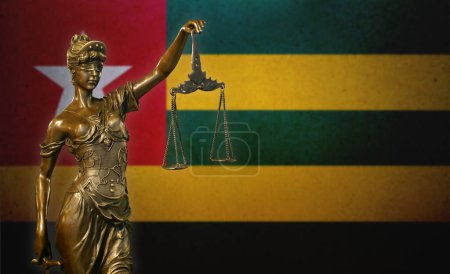 Nahaufnahme einer kleinen Bronzestatuette der Frau Gerechtigkeit vor einer Flagge von Togo.