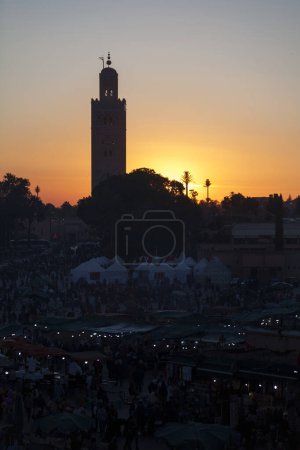 La Jemaa el-Fnaa en Marrakech al atardecer con la mezquita de Koutoubia detrás.