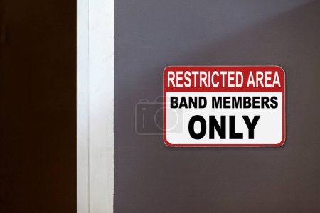 Red and white restricted area sign on the side of an open door stating : Restricted Area, band members only.