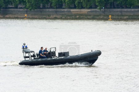Photo for London, England - June 05 2007: Two police officers from the Marine Police Force patrolling the Thames River with an inflatable raft near the House of Parliament. - Royalty Free Image