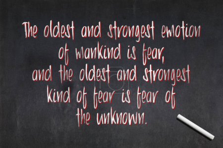 Blackboard with a quote from Lovecraft drawn in the middle saying "The oldest and strongest emotion of mankind is fear, and the oldest and strongest kind of fear is fear of the unknown.".