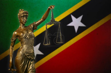 Nahaufnahme einer kleinen Bronzestatuette der Lady Justice vor einer Flagge von St. Kitts und Nevis.