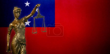 Nahaufnahme einer kleinen Bronzestatuette der Lady Justice vor einer Flagge Samoas.