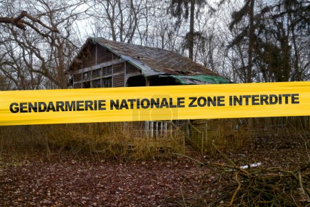 Téléchargez les photos : Cabane abandonnée dans les bois avec une bande de cordon avec écrit en français "Gendarmerie Nationale zone interdite". - en image libre de droit
