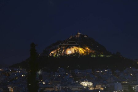 Cityscape of Athens by night with the Church of St George on top of Mount Lycabettus.