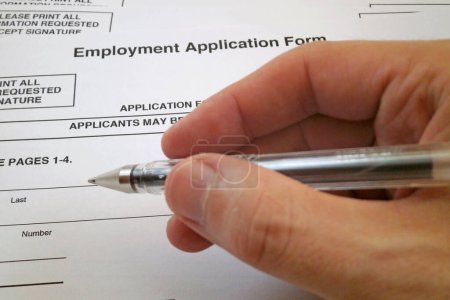 Ballpoint pen hold in the hand of a man filling an Employment Application Form.