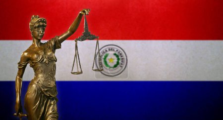 Nahaufnahme einer kleinen Bronzestatuette der Lady Justice vor einer Flagge Paraguays.