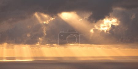 A sunburst shining through the clouds and reflecting on the Indian Ocean along the shore of Reunion Island.