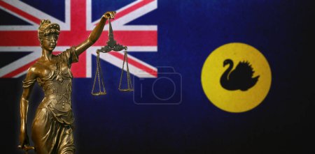 Nahaufnahme einer kleinen Bronzestatuette der Lady Justice vor einer Flagge Westaustraliens (Australien)).