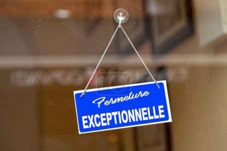 Téléchargez les photos : Panneau bleu ouvert accroché à la porte vitrée d'une boutique disant en français : "Fermeture exclusive", signifiant en anglais : "Exceptional closure". - en image libre de droit