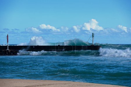 Jetty of the marina of Saint-Gilles les Bains during the summer solstice with giant waves passing above it.