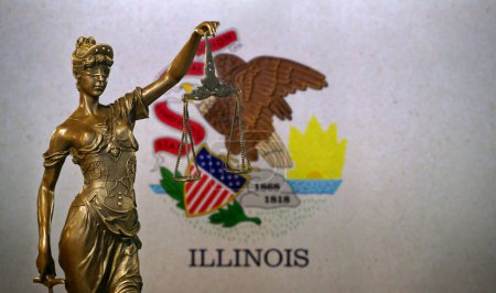 Nahaufnahme einer kleinen Bronzestatuette der Lady Justice vor einer Flagge von Illinois.