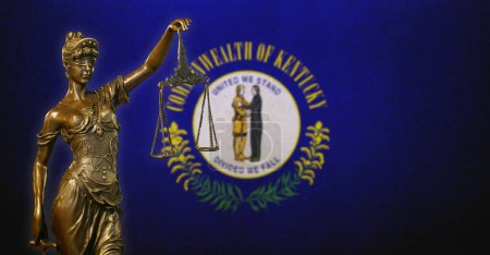 Close-up of a small bronze statuette of Lady Justice before a flag of Kentucky.
