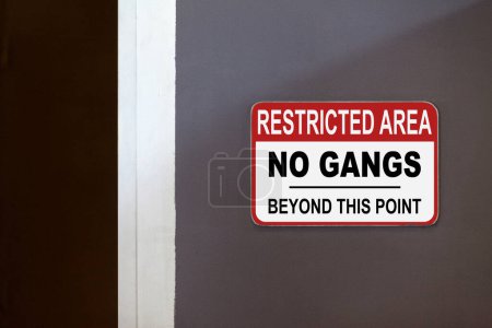 Panneau rouge et blanc de zone réglementée sur le côté d'une porte ouverte indiquant "Zone réglementée, Pas de gangs au-delà de ce point".