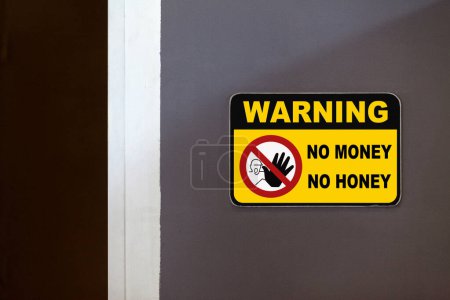 Yellow and black warning sign on the side of an open door stating in "Warning - No money No honey".