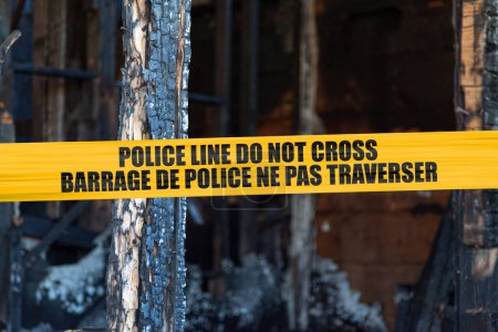 House burnt to the ground by a pyromaniac with a police tape with written in it in English "Police line do not cross" and French "Barrage de police ne pas traverser".
