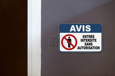 Blaues und weißes Hinweisschild an der Seite einer offenen Tür mit der Aufschrift "Avis, Entree interdite sans authorization", was auf Englisch "Hinweis, Einreise ohne Genehmigung verboten" bedeutet.".