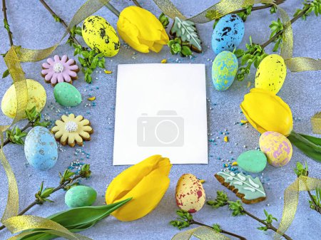Foto de Fondo de Pascua con tarjeta, huevos de Pascua, flores de tulipán, ramitas verdes, cinta amarilla sobre fondo azul. Copiar espacio, vista superior - Imagen libre de derechos