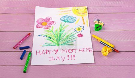 Foto de Dibujo infantil de saludos del Día de la Madre, lápices y papel sobre un fondo de madera rosa. Concepto del Día de la Madre Feliz. - Imagen libre de derechos