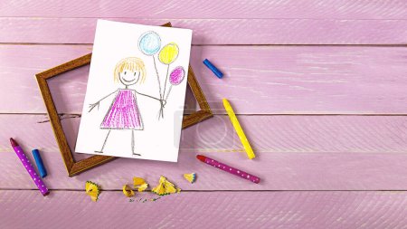 Foto de Dibujo infantil de saludos del Día de la Madre, marco de fotos, flor de tulipán púrpura y lápices sobre fondo de madera rosa. Concepto del Día de la Madre - Imagen libre de derechos