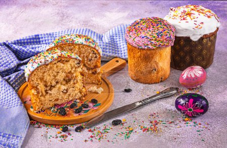 Foto de Un cupcake de Pascua cortado en una bandeja es una cocción tradicional ucraniana de vacaciones. Cuchillo, pasas, huevos de Pascua, espolvorea como decoración. Composición festiva de Pascua. - Imagen libre de derechos