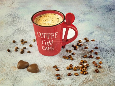 Foto de Una taza de café rojo con una cuchara, granos de café y chocolates sobre un fondo claro. Vista lateral. - Imagen libre de derechos