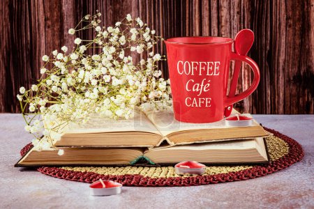 Foto de Bodegón con una taza de café rojo con una cuchara, libros, flores de gypsophila y velas sobre un fondo de madera. - Imagen libre de derechos