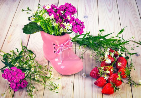 Foto de Zapato rosa y ramo de flores silvestres de verano, fresas rojas maduras en la mesa. Hola verano naturaleza muerta - Imagen libre de derechos