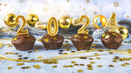 Foto de Feliz año nuevo 2024 concepto. Velas brillantes, magdalenas de chocolate, juguetes de árbol de Navidad, bolas y confeti dorado sobre un fondo azul - Imagen libre de derechos