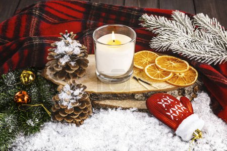Téléchargez les photos : Nature morte confortable d'hiver avec bougie blanche, gant de jouet d'arbre de Noël, cônes enneigés, oranges séchées, écharpe en laine. - en image libre de droit