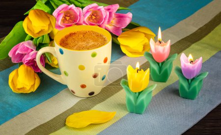Spring bouquet of pink and yellow tulip flowers, flower petals, tulip candles on a striped tablecloth. Spring still life