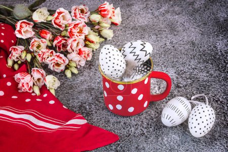 Easter composition with white and black polka dot eggs in a red and white polka dot cup, eustoma flowers, red shawl. Happy Easter.