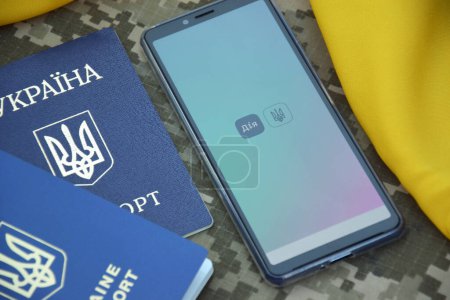 Photo for Kharkiv, Ukraine - October 18, 2022: Diia app on smartphone screen on military pixel background. Diya is a mobile application with a web portal and a brand of e-government in Ukraine for citizens. - Royalty Free Image