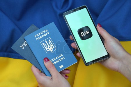 Photo for Kharkiv, Ukraine - October 18, 2022: Diia application on the smartphone screen against the background of the flag of Ukraine. Action is a mobile application with a web portal and a brand of e-government in Ukraine for citizens. - Royalty Free Image