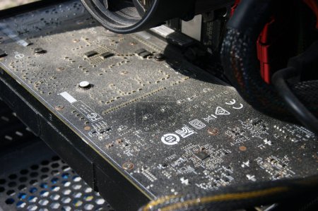 Foto de KHARKOV, UCRANIA - 10 DE MAYO DE 2020: Limpieza de una tarjeta de vídeo muy polvorienta AMD Radeon R7 200 Series con un cepillo. Enfoque selectivo. - Imagen libre de derechos