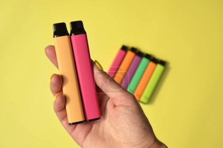 Set mehrfarbiger elektronischer Einwegzigaretten auf leuchtend gelbem Hintergrund. Das Konzept des modernen Rauchens, Dampfens und Nikotins.
