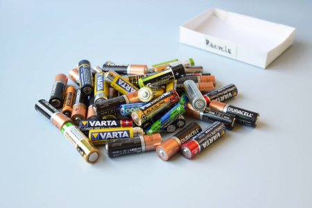 Photo for KHARKIV, UKRAINE - February 22, 2022: Used AA batteries and proper disposal of environmentally and soil toxic batteries on a blue background. The concept of processing harmful and recyclable objects. - Royalty Free Image