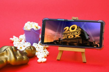 Téléchargez les photos : KHARKIV, UKRAINE - 1er JUIN 2020 : Smartphone avec logo studio du 20ème siècle, figurine Oscar et pop-corn. Concept d'industrie cinématographique. - en image libre de droit