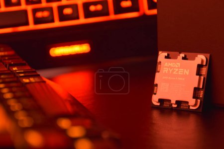Photo for UKRAINE, KHARKIV, NOVEMBER 14, 2022: A close-up of an AMD Ryzen 9 7900X processor in a packaging box with backlit keyboards in the background. - Royalty Free Image