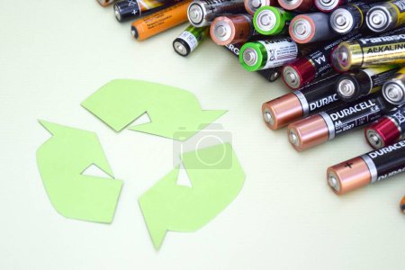 Photo for KHARKIV, UKRAINE - JUNE 11, 2022: Used AA batteries and proper disposal of environmentally and soil toxic batteries on a green background. The concept of processing harmful and recyclable objects. - Royalty Free Image