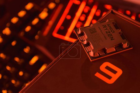 Photo for UKRAINE, KHARKIV, NOVEMBER 14, 2022: A close-up of an AMD Ryzen 9 7900X processor in a packaging box with backlit keyboards in the background. - Royalty Free Image