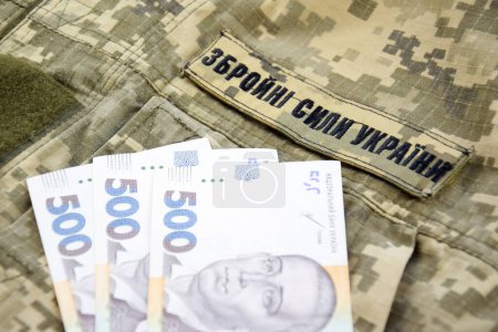 Ukrainian hryvnia against the background of a military pixel with the inscription of the armed forces of Ukraine. The concept of wages, payments and donations to the military.