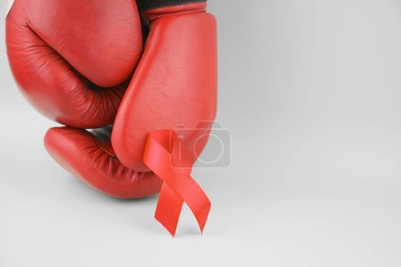 Photo for Red ribbon with boxing gloves, wrestling symbol. World AIDS Day and National HIV, AIDS and Aging Awareness Month. - Royalty Free Image