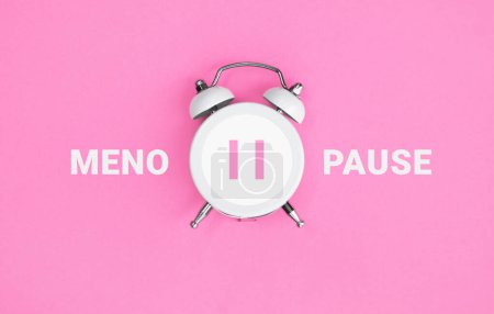 Foto de Reloj despertador vintage blanco con inscripción MENOPAUSE sobre fondo rosa. Salud de las mujeres. Puesta plana. - Imagen libre de derechos