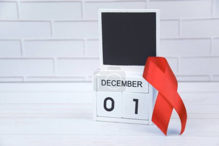 Photo for Red ribbon with calendar, symbol of struggle. December 1 is World AIDS Day and National HIV, AIDS and Aging Awareness Month. - Royalty Free Image
