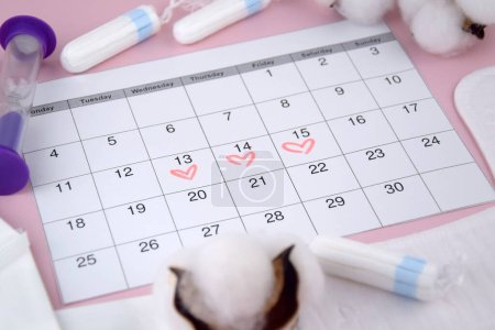 Almohadillas menstruales de las mujeres, tampones, calendario de menstruación femenina y reloj despertador sobre un fondo rosa. Período de días críticos. Lugar para el texto.