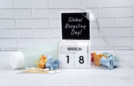 Wooden calendar with the date March 18 with paper and plastic. World Recycling Day.
