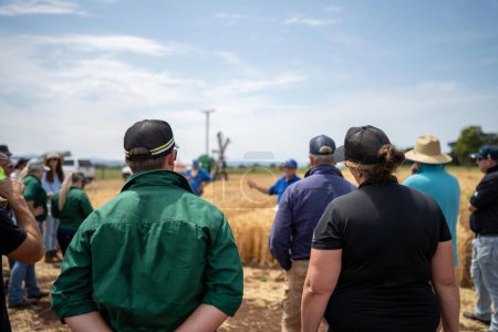 Foto de Grupo de agricultores en un campo que aprenden sobre los cultivos de trigo y cebada de un agrónomo con plantaciones de ensayo - Imagen libre de derechos